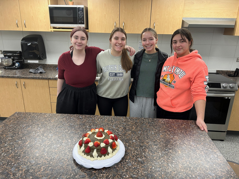 students posing with their cake